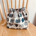 Detail of a thick linen drawstring bento bag with Japanese cat patterns on a wooden chair - White Blue Cat Head