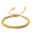 Detailed shot of handmade braided golden knot bracelet with colorful ethnic thread accents - Multicolor and Golden Yellow