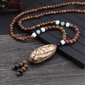 Ethnic style necklace with brown wooden beads and large patterned oval pendant charm - Thousand Eye Bodhi