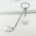 Detailed close-up of a golf club and ball keychain with silver metallic finish and ring - White