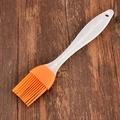 Pincel de silicona naranja con mango blanco sobre fondo de madera rústica - Naranja