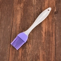 Pincel de silicona morado con mango blanco sobre fondo de madera oscura para BBQ - Morado