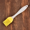 Yellow silicone oil brush with white handle for BBQ and baking on wooden background - Yellow