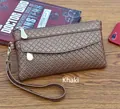 Detail of khaki clutch bag with woven pattern and dual zippers on wooden table - Khaki