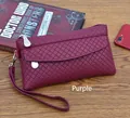 Close-up of purple wristlet bag with woven texture and front zipper pocket on wooden table - Purple
