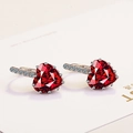 Macro shot of silver earring featuring a large heart-shaped red gemstone and zircon accents - Red Zirconia