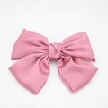 Nahaufnahme einer großen rosa Satin-Schleife Haarspange mit eleganter Seidentextur auf Weiß - Rosa Federclip