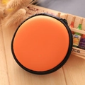Orange circular EVA storage pouch with black zipper on light wood background - Orange