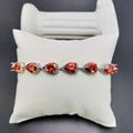 Elegant silver bracelet featuring pear-cut red zircons displayed on a premium white pillow - Garnet Red