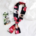 Détail d'un foulard en soie abstrait rouge et noir noué sur un fond en textile blanc - Peinture à l'Huile Rose Rouge