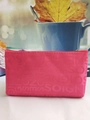 Detailed close-up of pink textured fabric makeup bag with SOIGNE embossed pattern - Rose Red