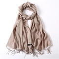 Macro shot of light beige cashmere scarf showing soft texture and fine fringe details - Camel