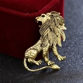 Close-up of golden vintage lion brooch with detailed leaf-shaped mane on black surface - Antique Gold