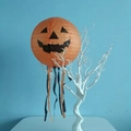 Close-up of orange Jack-o-lantern paper lantern with hanging ribbons on white branches - Pumpkin With Tassels