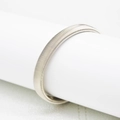 Detailansicht der silbernen Metall-Federarmspange mit feiner Textur auf weißem Stand - Silber