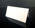 Close-up of a white laser-cut hollow heart table place card for wedding reception - White