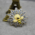 Macro d'une broche marguerite en émail avec un petit détail d'abeille sur du feutre - Gris Perle