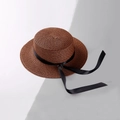 Dettaglio di un cappello di paglia marrone scuro con fiocco in nastro nero su sfondo - Bambini / Caffè Scuro