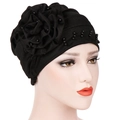 Turbante nero con grande fiore in tessuto e decorazioni di perline lucide su una testa di manichino - Nero