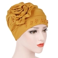 Detail of a ginger yellow turban hat with large side flower and orange pearls decor - Yellow