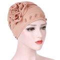 Turbante rosa con grande fiore in tessuto e perle su una testa di manichino - Cachi
