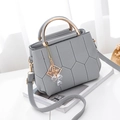 Grey embroidered crossbody bag with golden metal handles on white desk background - Light Gray
