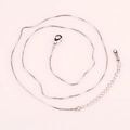 Détail d'un collier chaîne box argenté avec un fermoir mousqueton et une extension réglable - boîte chaîne / Argenté