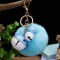 Porte-clés pompon bleu avec trois cloches en métal et crochet doré sur un fond naturel - Emballage unique en sac OPP / Cloche Bleue Blanche + Bleu Ciel