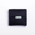 Portable black foldable Oxford cloth shopping bag in square folded state with BAG label - Black