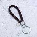 Makroaufnahme von handgeflochtenem dunkelbraunem Leder-Schlüsselanhänger mit Silberring - Dunkelbraun