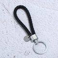 Detailaufnahme von schwarzem Leder-Schlüsselanhänger mit silbernem Metallring und Anhänger - Schwarz