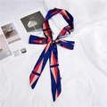 Close-up of a dark blue satin scarf with red geometric patterns tied in a bow on a magazine - Geometric Blue