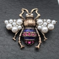Vista macro de broche de abeja vintage con perlas, esmalte azul y cristales rosas - Broche de Abeja