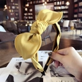 Handheld yellow fabric bow headband featuring a minimalist wrapped design and black inner base - Yellow