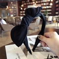 Handheld view of a simple black fabric rabbit ear bow headband for women - Black