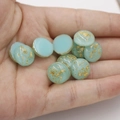 Detail of 12mm blue-green synthetic opal stones with gold foil flakes on a palm - Teal with Gold Foil (4)