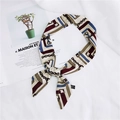 Slim silk scarf with classic chain print tied in a bow on a beige background - 26 Chain White