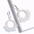 Detail of white beaded hoop earrings with intricate handmade woven patterns and metal hooks - White