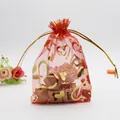 Macro shot of red organza gift bag featuring gold heart patterns and drawstring closure - Red