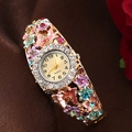 Detailed close-up of a gold floral bangle watch with colorful crystals and enamel flowers - Multicolor/Gold