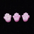 Macro view of three pink opal Hamsa hand charms for jewelry making on black velvet - Hamsa Hand No Hole / Pink