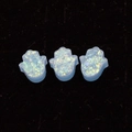 Makroaufnahme von drei blauen synthetischen Opal Hamsa Hand Anhängern auf schwarzem Samt - Hamsa Hand Ohne Loch / Hellblau