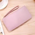 Elegant soft leather long wallet in pastel pink with handle on a wooden table - Pink Purple