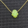 Macro shot of gold Hamsa hand pendant necklace with green synthetic opal inlay detail - Yellow-Green