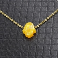 Macro shot of gold necklace with orange Hamsa hand opal pendant on black leather - Orange