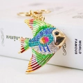 Golden fish keychain with colorful enamel and crystal rhinestones on a book background - Blue