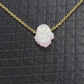 Nahaufnahme der goldenen Kette mit schillerndem weißen Opal-Hamsa-Anhänger auf dunklem Grund - Rosa Weiß
