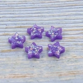 Close-up of five purple star-shaped resin opal beads with iridescent glitter for DIY jewelry - Purple