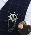 Dettaglio della spilla nautica con timone, ancora e catene sul bavero della giacca - Argento