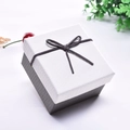 Detail of square bow-knot gift box featuring white lid and textured grey base - With Small Pillow / White and Grey